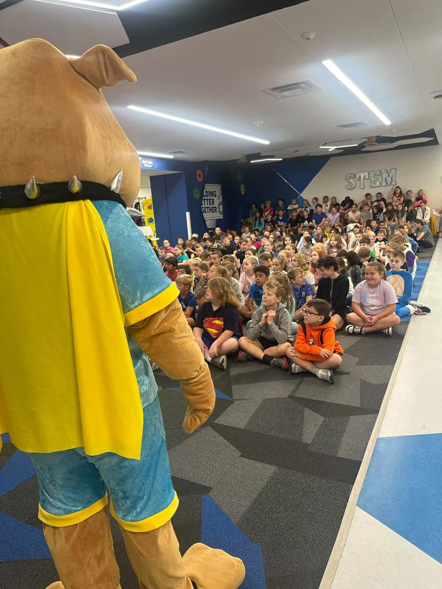 CHOMP mascot in front of the school assembly