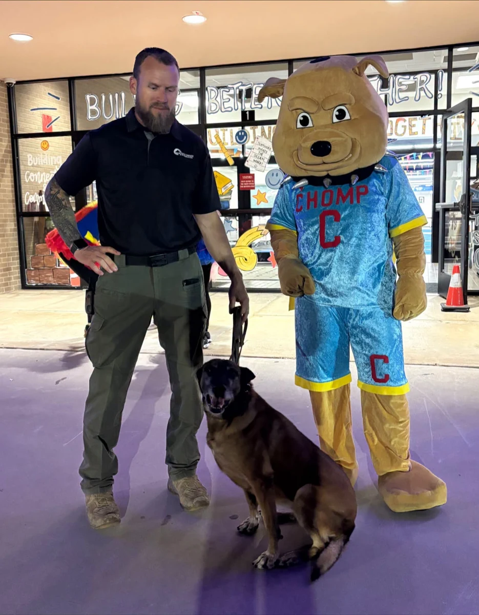 An officer and dog posing with the CHOMP mascot