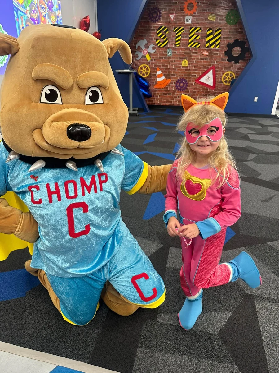 A costumed student posing with the CHOMP mascot