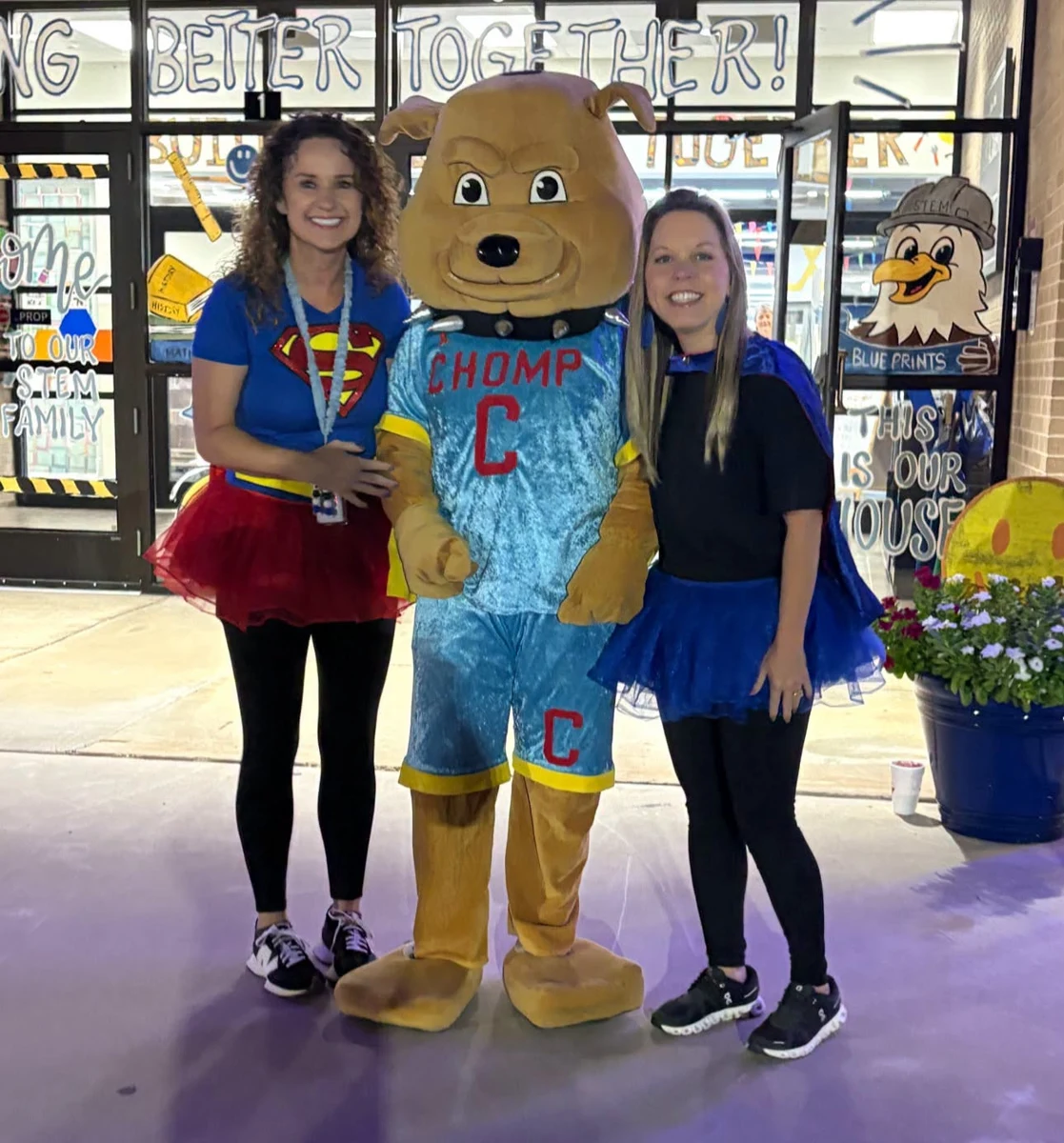 Two presenters posing with the CHOMP mascot